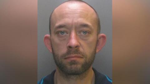 Mugshot of Martin Jackson. He is bald with faint dark hair and black beard.