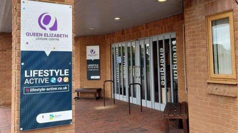 Covered entrance to the leisure centre with glass and metal doors and pale-coloured bricks