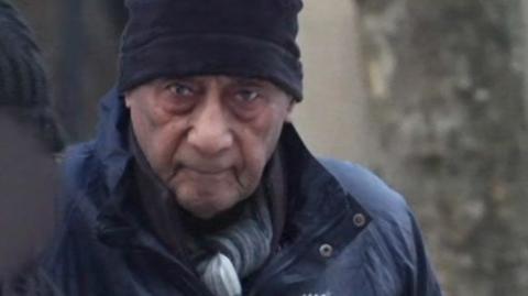 Malcolm Phillips head and shoulders image wearing a coat and hat while arriving at court in a grab from footage