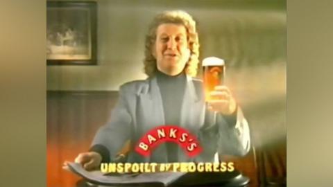 Singer Noddy Holder in an old TV advert for Banks's. He is holding a pint with a paper and a slogan saying "Unspoilt by Progress".