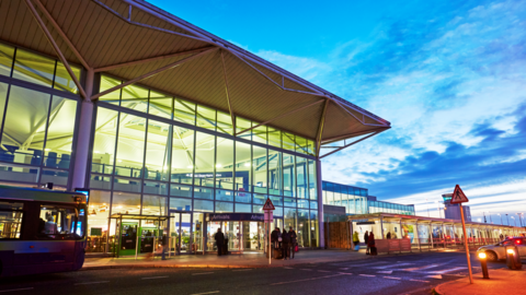 A picture of the exterior of Bristol Airport, taken at dusk, showing the front of the main terminal illuminated