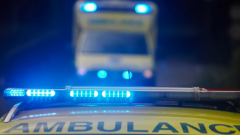The blue lights on top of a yellow ambulance vehicle.