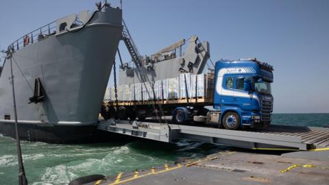 File photo showing a lorry disembarking a US military vessel and moving onto a floating pier attached to Gaza's coast (13 June 2024)