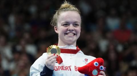 Great Britain's Maisie Summers-Newton celebrates with her gold medal after winning the Women's 100m Breaststroke - SB6 Final at the Paris La Defense Arena on day four of the Paris 2024 Summer Paralympic Games