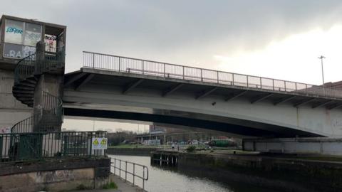 A close image of the Plimsoll Swing Bridge stuck open at a slight angle beside a spiral staircase. 