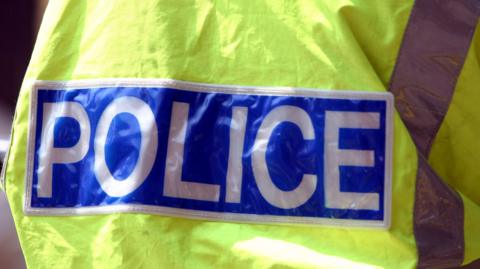 A police high-vis jacket with police written in white block capital lettering on a blue background.