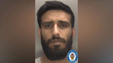 A mugshot of a man with dark brown hair styled to one side, brown eyes, and a dark brown beard and moustache. It has a West Midlands Police badge in one corner.