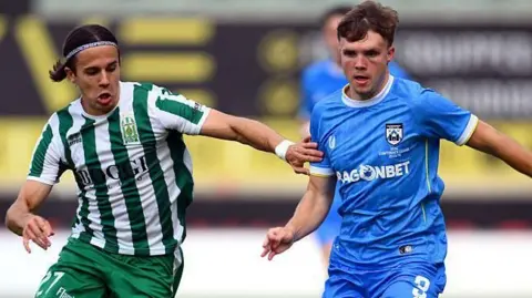 Rhys Abbruzzese of Haverfordwest County is challenged by Todor Glisovic of Floriana