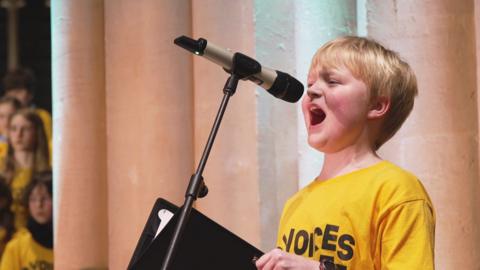 a child singing in a choir on stage