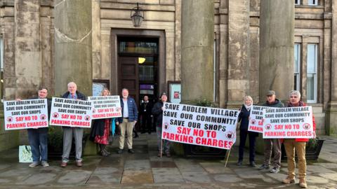 Protesters holding signs against parking charges outside Macclesfield town hall