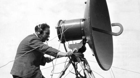 A man wearing a headset operating a satellite.