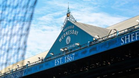 A view from inside Sheffield Wednesday's Hillsborough stadium of a stand roof bearing the club's name and a clock