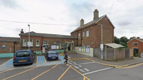 A brick building. It is a train station. The sky is grey. 