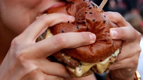Close up of a cheeseburger being eaten outside