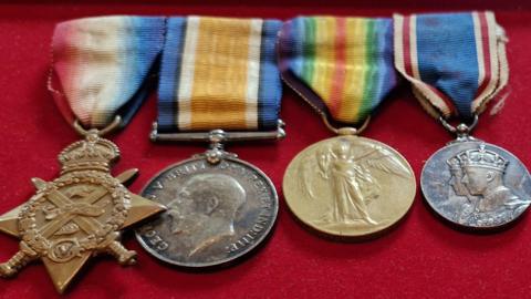 Four metal military medals, featuring colourful striped ribbons