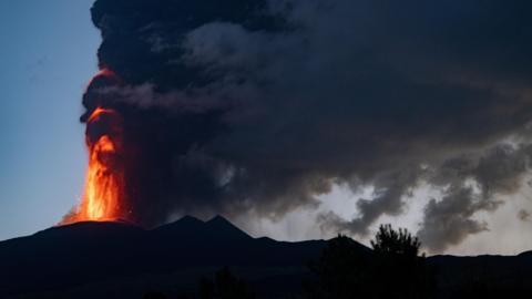 Mount Etna spewing lava upwards, with lots of steam