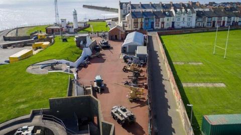 An aeriel view of the Heugh Battery Museum in Hartlepool. 
In the centre there is a selection of war tanks, in the background you can see the sea.