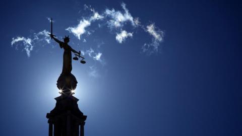 A state of Lady Justice on top of the Old Bailey / Central Criminal Court, with a blue sky in the background.