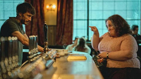 Baby Reindeer stars Richard Gadd and Jessica Gunning, sat across a bar 