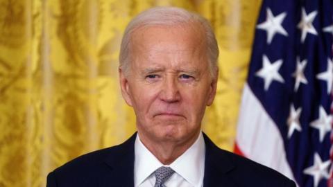 Joe Biden standing in front of a US flag