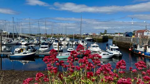 Mainly blue sky over a harbour with small boats 