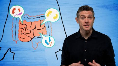 Man in a dark shirt with illustration of the gut behind him