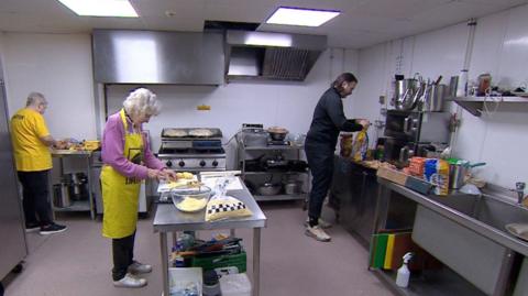 Three volunteers preparing food