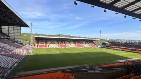 A football ground on a sunny day. Coloured seats in the far stand read 'Bantams'