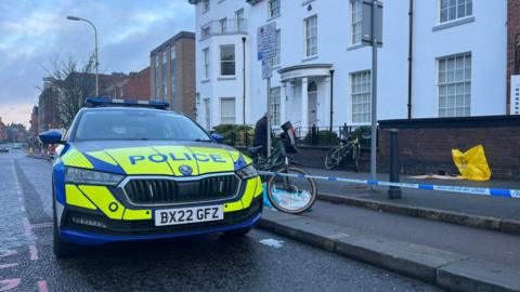 Two bikes inside the cordon at the scene in London Road. A police car is pictured in the road next to the cordon. 