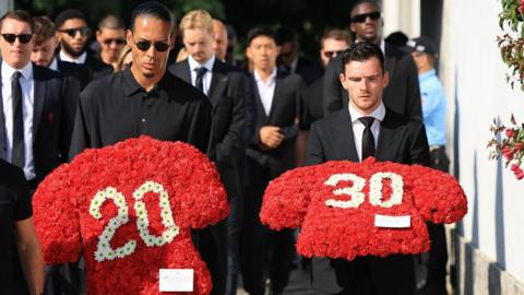 Liverpool players Virgil van Dijk (C) and Andy Robertson (R) carry floral tributes 