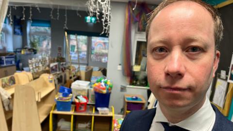 Neil Bardsley stood with a classroom in the background affected by flood damage