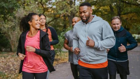 Group of people running through a park.