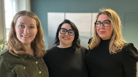 Birth Trauma North East directors Lucie Pitman, Lottie King and Leanne Kast.
Ms Pitman is wearing a green shirt has blond hair. Ms King has dark shoulder-length and is wearing a black top. Ms Kast has blonde hair and is wearing dark glasses and a black top.