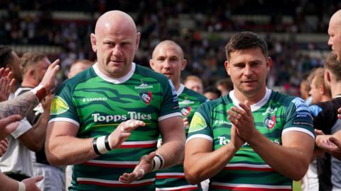 Dan Cole and Ben Youngs standing next to each other on a pitch. They are both dressed in green rugby kit and are both clapping.