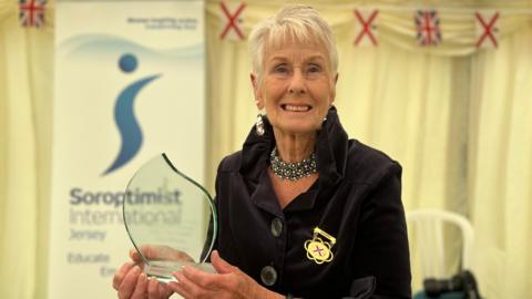 Joy smiles at the camera as she holds her award