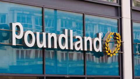 Retail store signage which read Poundland in white letters against a light green backdrop. There is a yellow wheatsheaf emblem alongside the lettering.