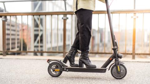 A woman rides an electric scooter on a city street.