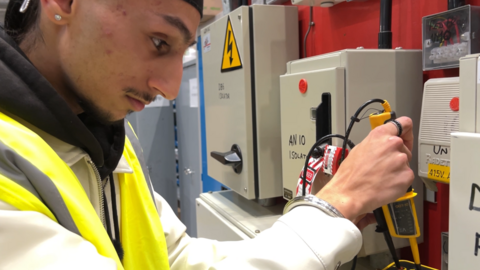 19 year old Prem Singh Dhamrait carries out an electrical procedure at Dudley College. He is wearing  cream jacket and a hi-vis vest