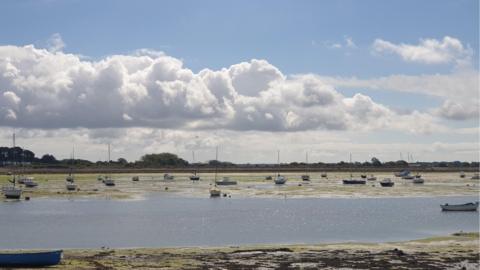 Clouds building above the coast with boats resting in shallow waters