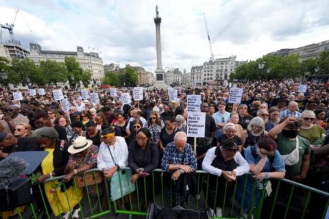 A crowd of people gather in Trafalgar Square as part of a vigil for Jason Arday. Some of them are holding placards.