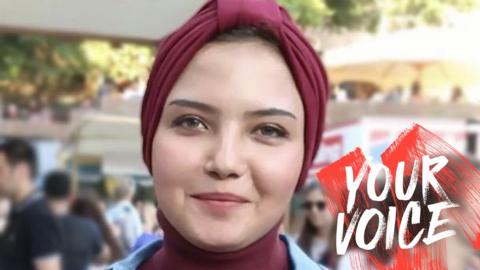 Susan Nasser, a young woman wearing a burgundy turban, pictured outside with people in the background. The words YOUR VOICE have been imposed on the photo on the right hand side.