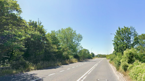 The A370 tarmac road between green trees. It is empty.
