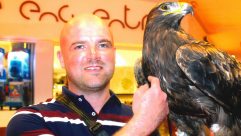 A man in a blue red and white striped shirt holding an eagle