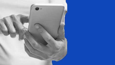 A person using a mobile phone in front of a blue background.