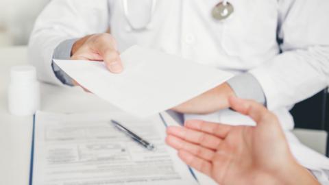 Doctor handing a piece of paper to a hand off screen