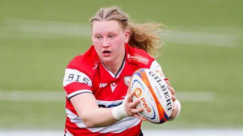 Alaw Pyrs, in action for Gloucester-Hartpury, with the ball out in her hands in front of her body.