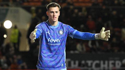 Radek Vitek standing on the pitch with his arms stretched out wide in front of him