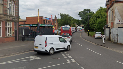 A generic view of Station Road in Erdington. A car wash business is visible, and queue of traffic is waiting at traffic lights.  