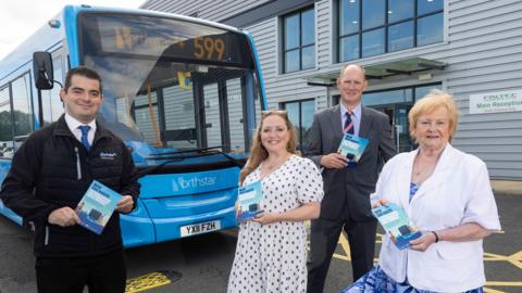 Four people standing in front of a blue bus