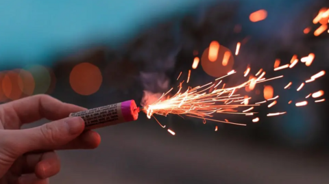A hand holding a lit firework